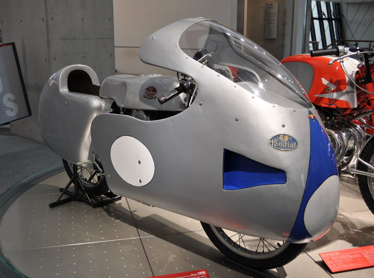 Silver 1956 FB Mondial 125 GP racer with a dustbin fairing and blue nose, displayed at the Honda Collection Hall