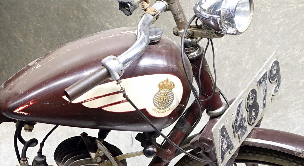 Maroon tank of a c.1938 Husqvarna lightweight with a gold crowned Gothic H shield and the word HUSQVARNA on a cream panel with maroon stripes