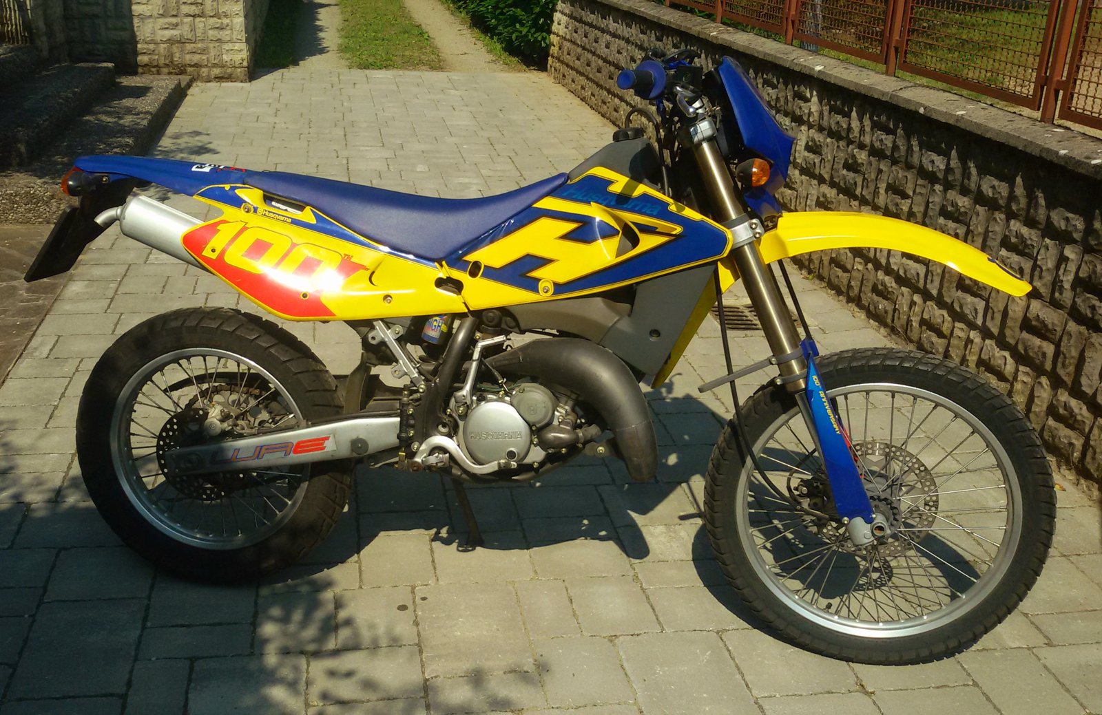 Yellow and blue 2004 Husqvarna WRE 125 centenary model with a large stylised H on its side panel
