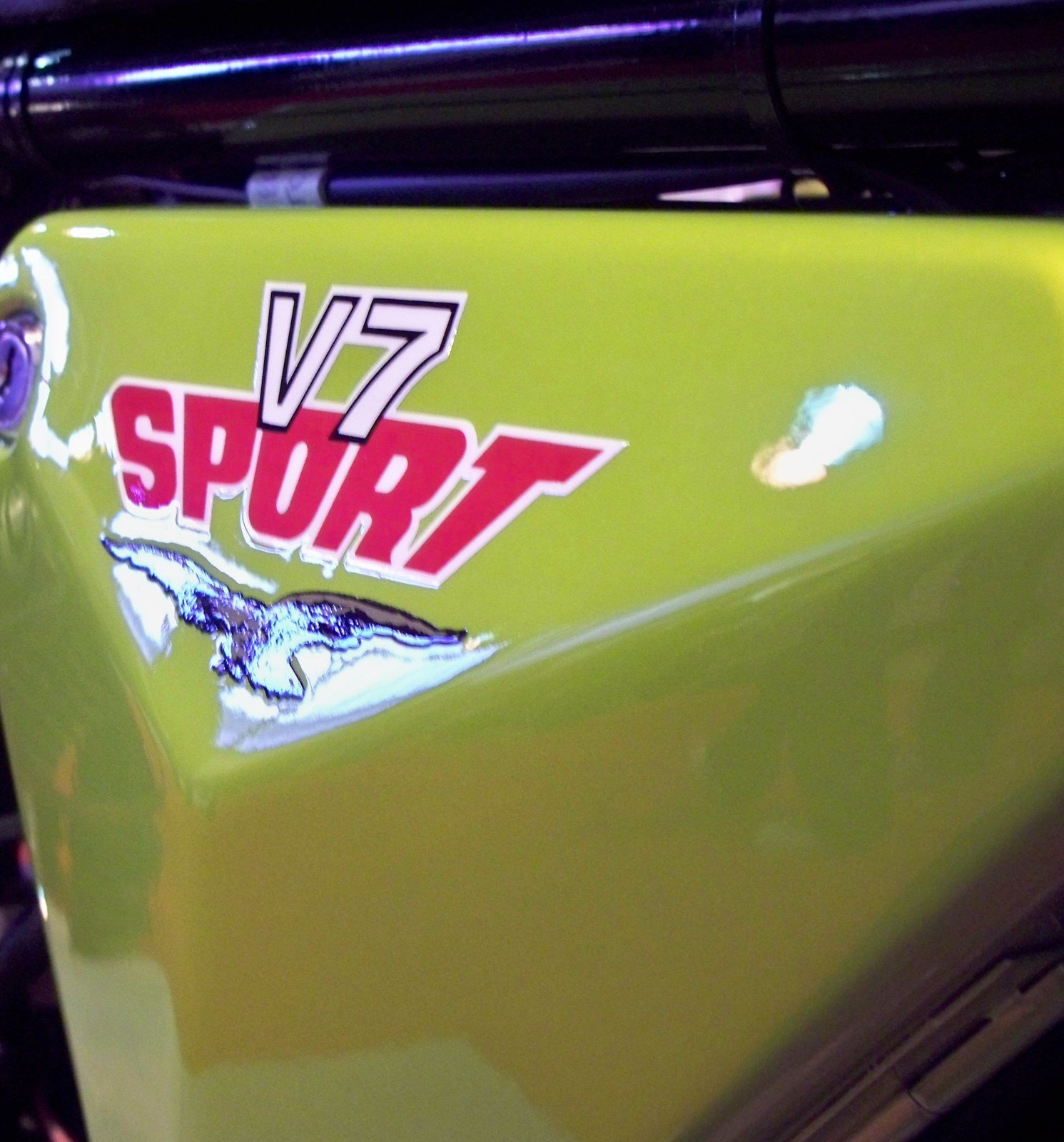 Lime-green side panel of a Moto Guzzi V7 Sport with red and white V7 Sport lettering above a chrome-foil eagle