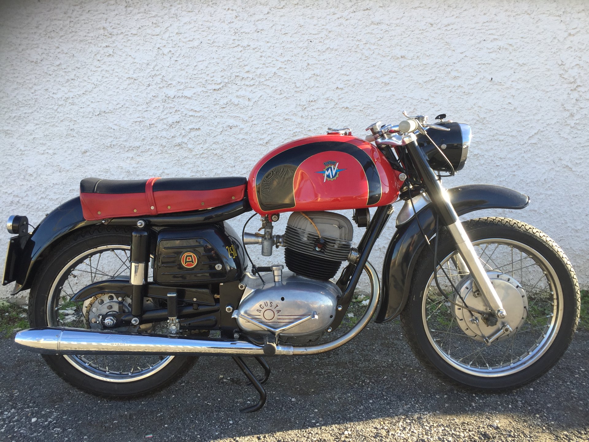An MV Agusta 250 Raid with a red tank and black knee panels lined in gold, the crest centred on the red section