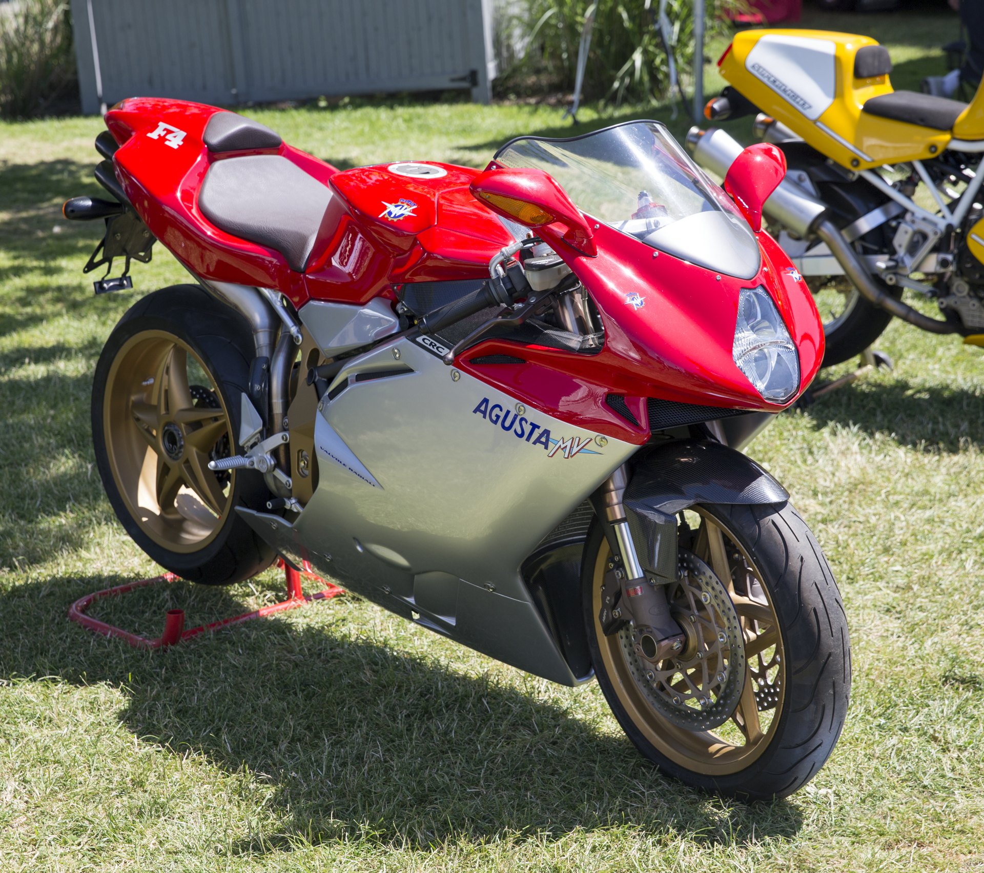 A red and silver 1999 MV Agusta F4 Serie Oro with gold wheels, showing the crest on the tank and AGUSTA MV lettering on the silver lower fairing