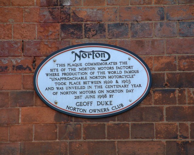 Oval blue plaque on a brick wall in Bracebridge Street, Birmingham, with the Norton curly N and text commemorating the Unapproachable Norton factory