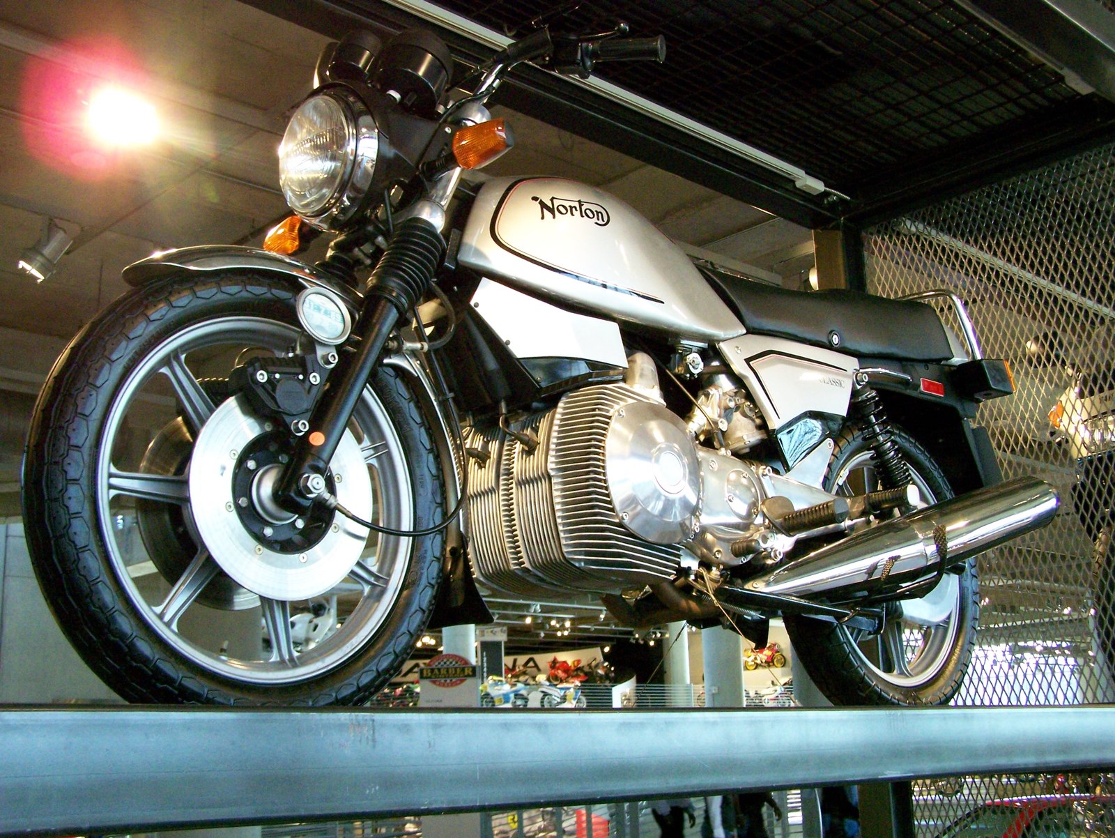 A Norton Classic rotary with a silver tank carrying a black curly N and a thin black pinline, displayed on a balcony at the Barber museum