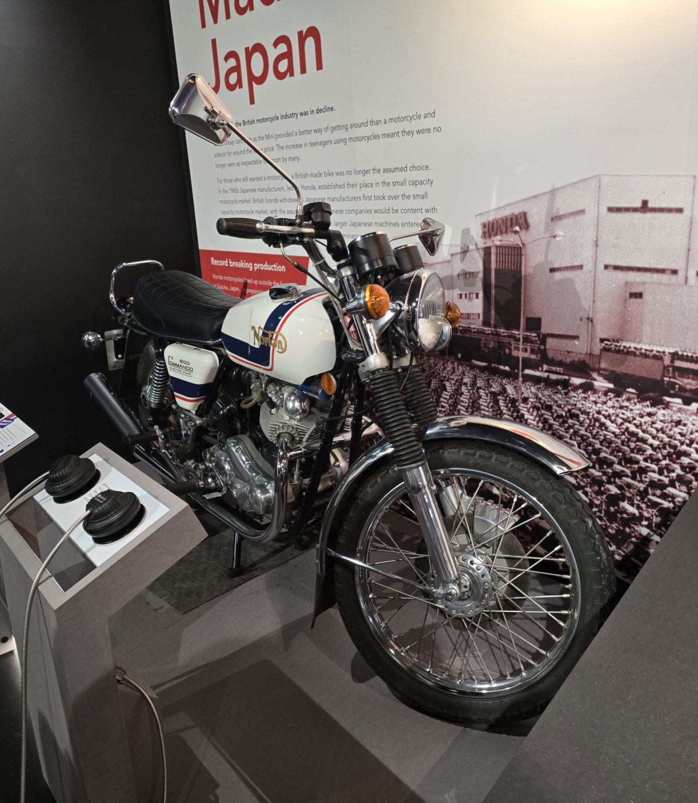A 1977 Norton 850 Commando Electric Start in a museum display, with a white tank carrying a gold curly N and red and blue stripes