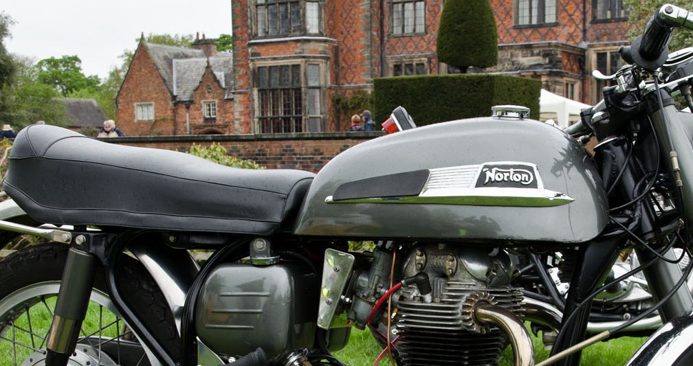 Grey tank of a 1968 Norton Dominator 650SS with a long ribbed chrome badge ending in a black plate with a chrome curly N Norton script