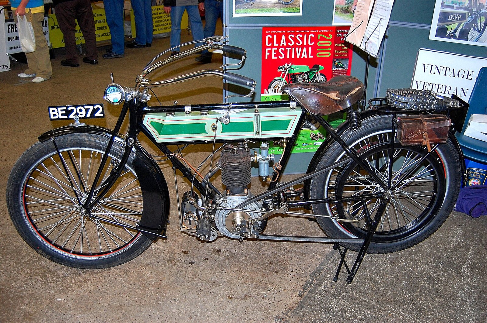 A restored Triumph Model H with a green and cream tank and belt drive, displayed at a show