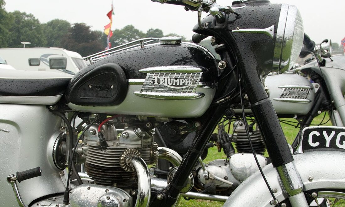 Black and silver tank of a 1964 Triumph 5TA Speed Twin with a chrome mouth-organ badge of horizontal bars carrying the TRIUMPH wordmark