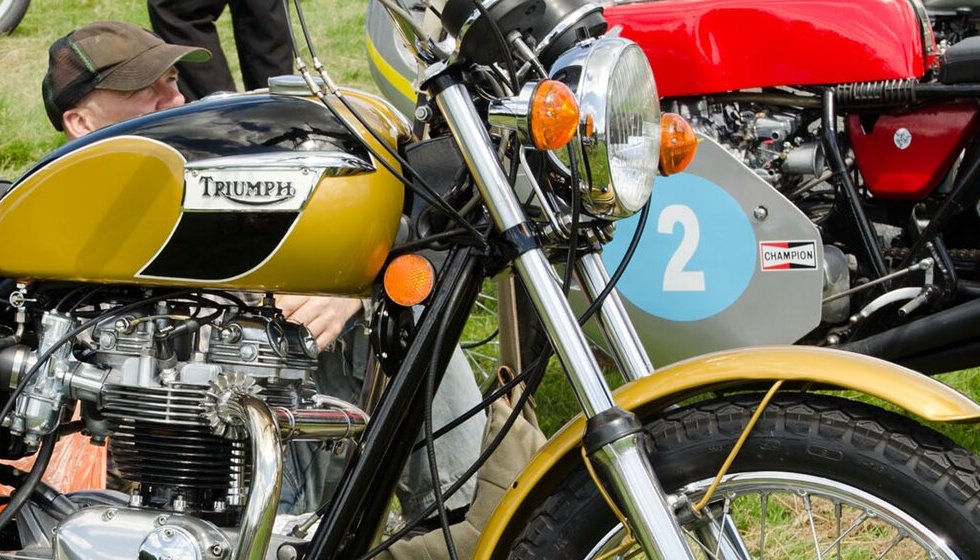 Gold and black tank of a 1972 Triumph T120 Bonneville with a chrome-framed TRIUMPH badge