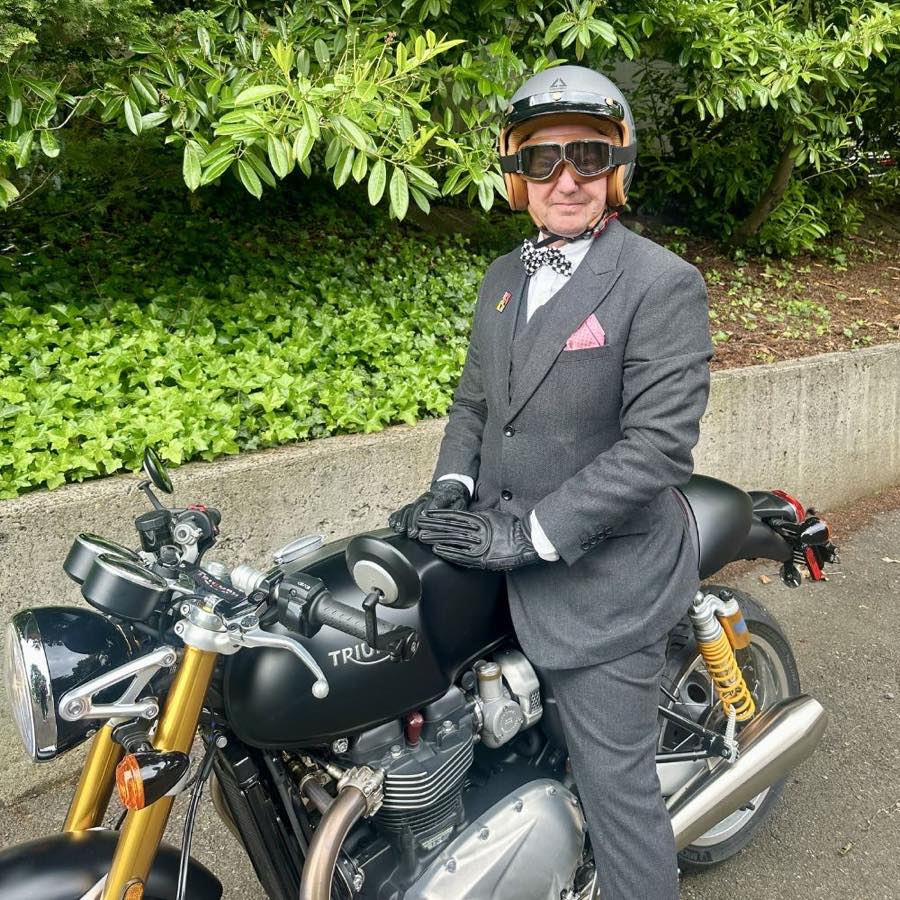 William Flaiz in tweed and open-face helmet astride his Triumph café racer