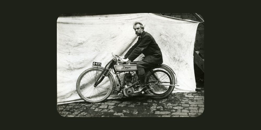 A man is riding a motorcycle on a cobblestone street.